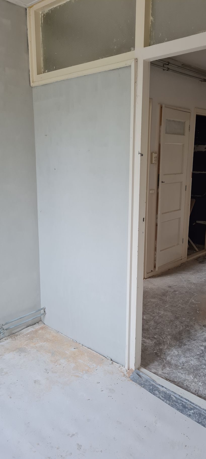 Binnendeur met onafgewerkte gipsplaten en kozijnen, die een kamer in aanbouw laat zien.