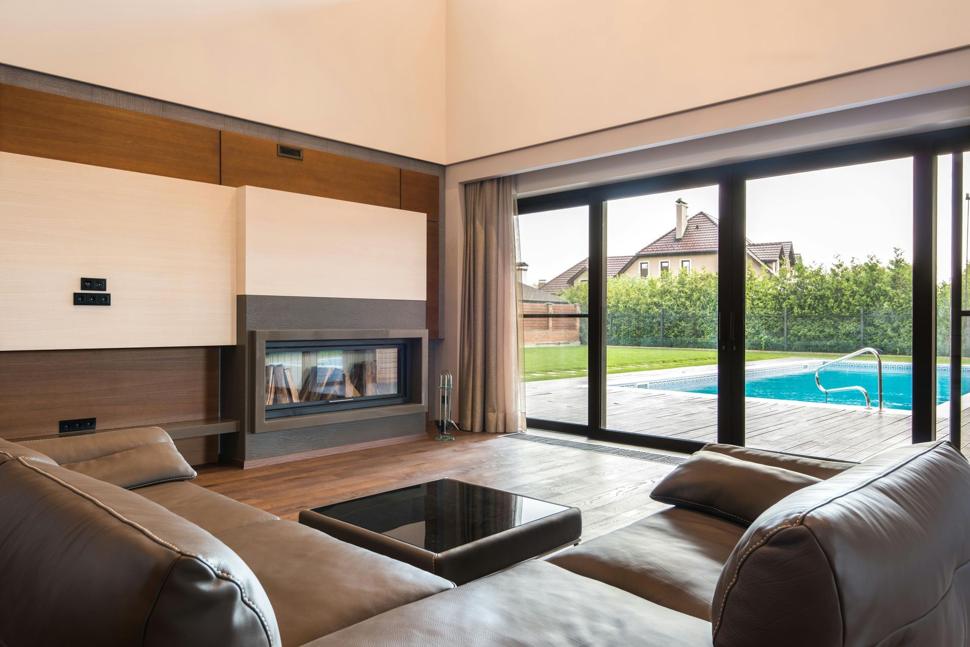 Modern living room with a fireplace and sliding glass doors overlooking a pool.