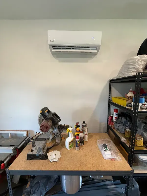 Workbench with tools and bottles under a wall-mounted air conditioner in a garage or workshop