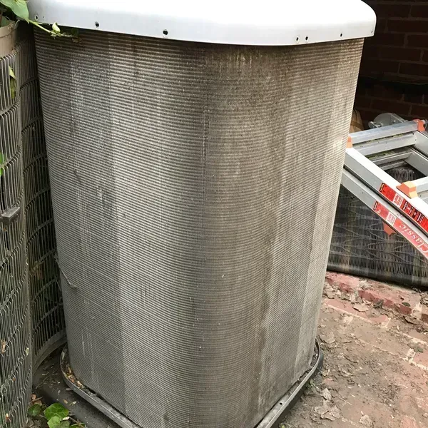 Outdoor air conditioner condenser unit with a dusty metal grille and white top cover