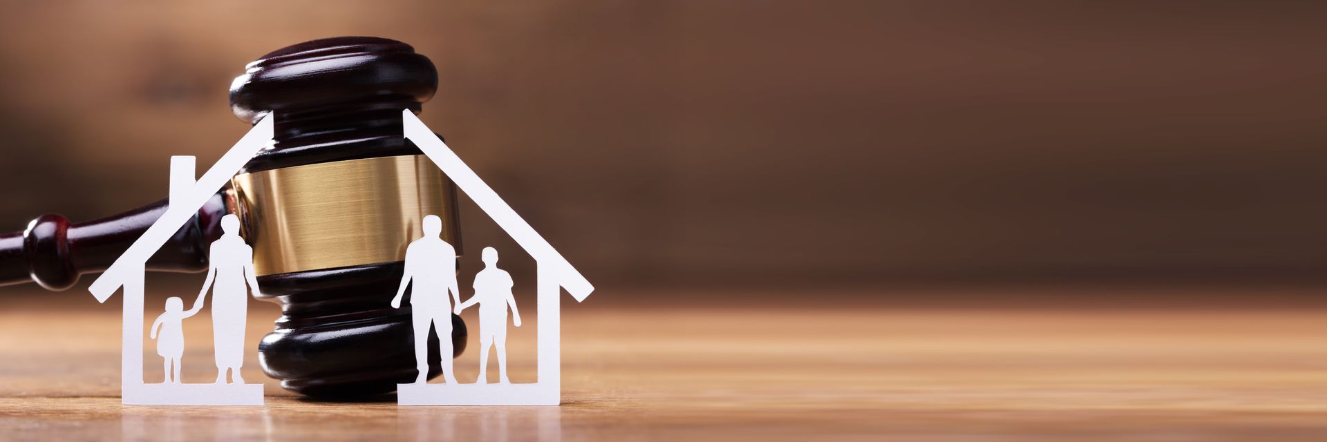 Court gavel beside house-shaped family icons on a wooden surface, symbolizing legal family matters