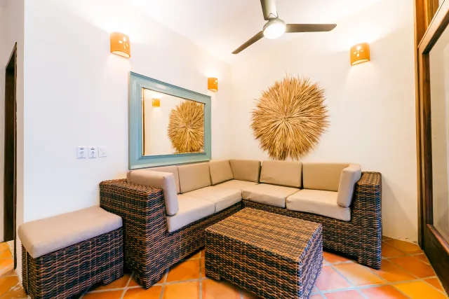 Cozy outdoor seating area with wicker furniture, neutral cushions, and decorative wall art.