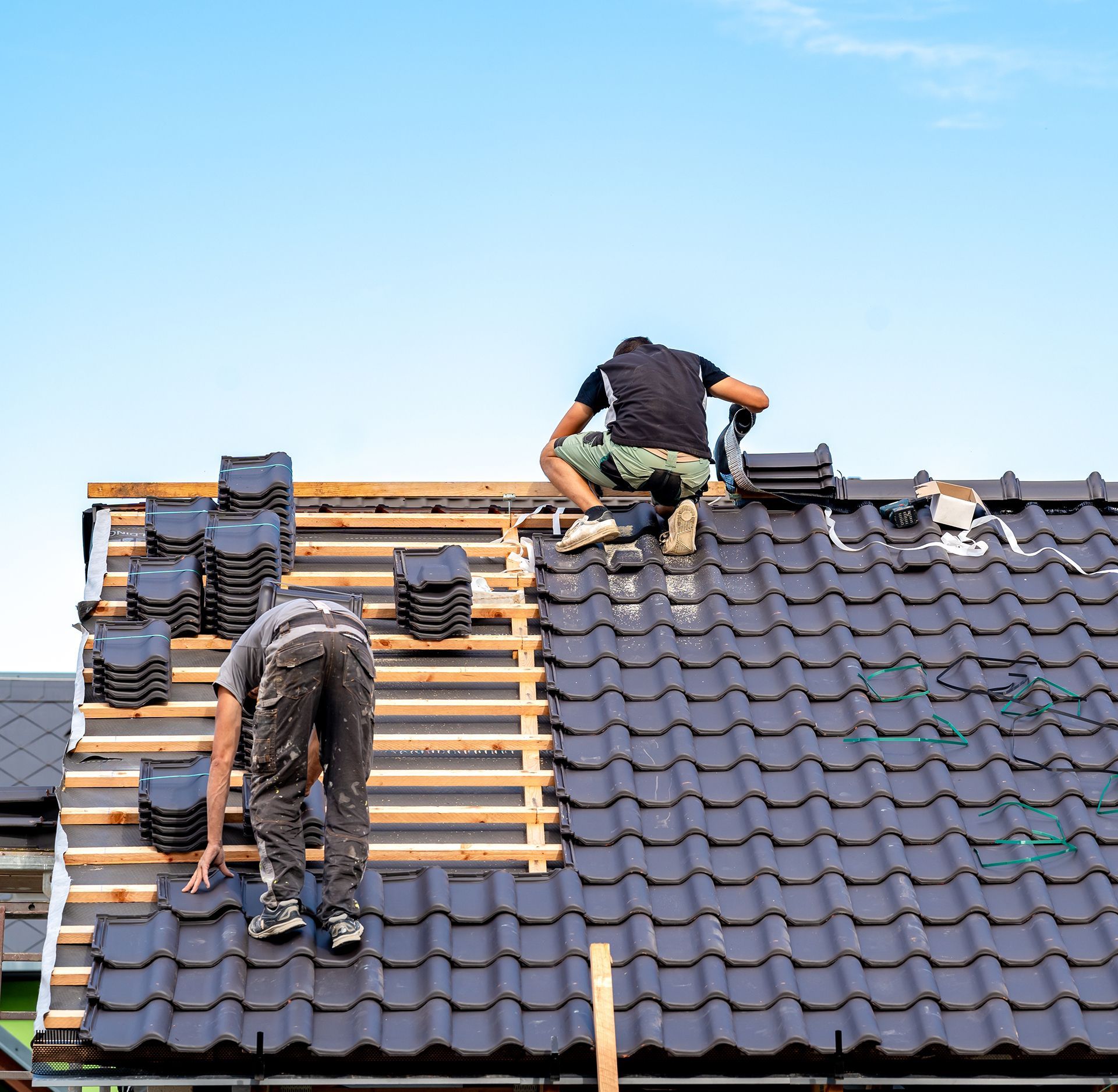 Two men are working on the roof of a house.