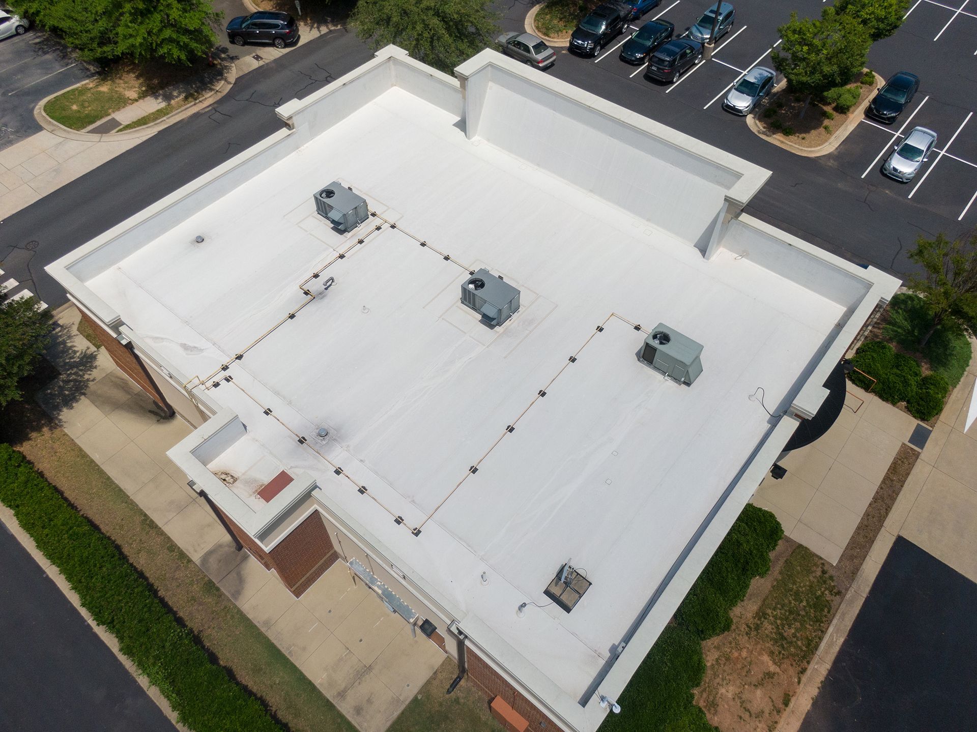 An aerial view of a white roof of a building in a parking lot.