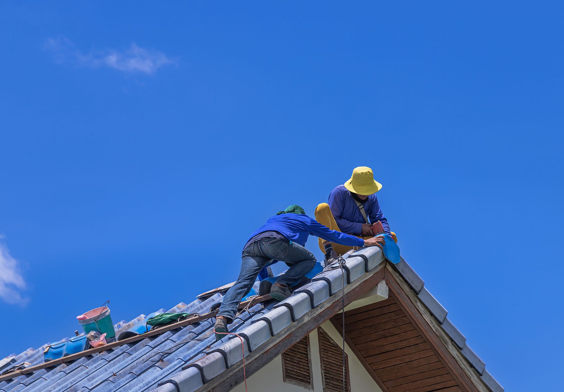Two men are working on the roof of a house.