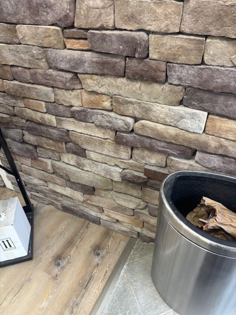 Stone veneer wall with wooden accents, and a metal container.