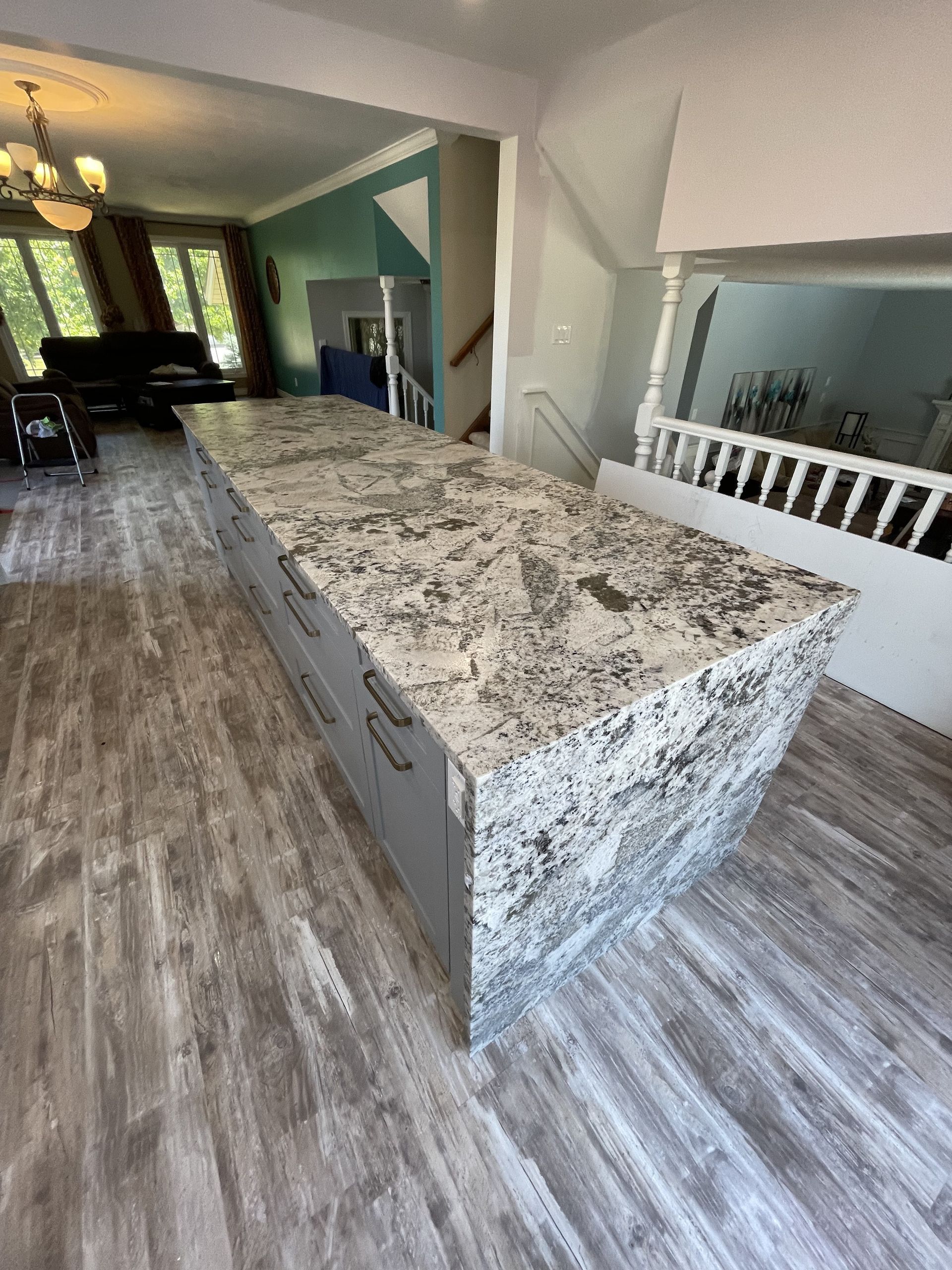 Kitchen island with granite countertop and gray cabinets. Light gray flooring.
