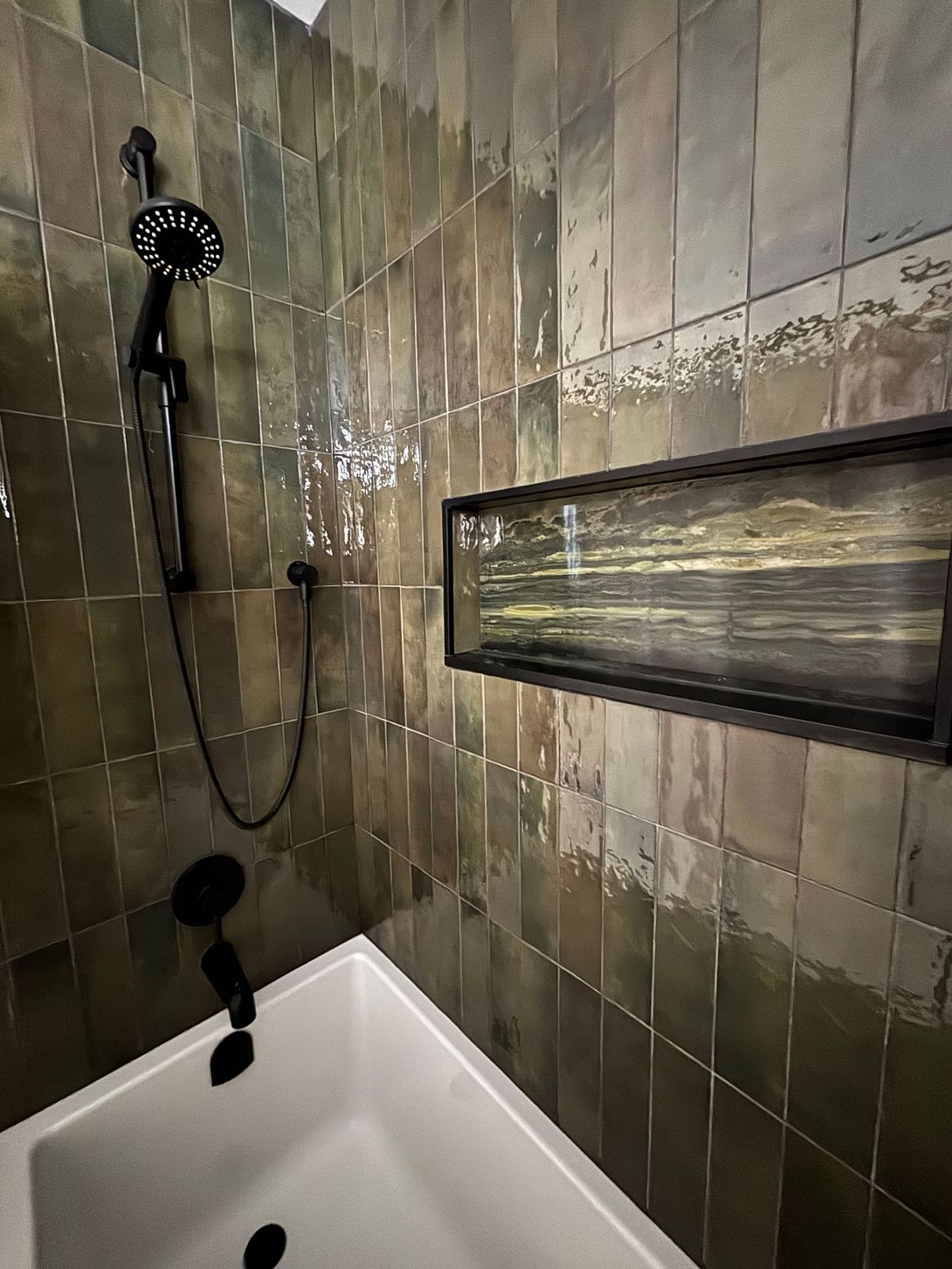 A bathroom with a bathtub , shower , and shelf.