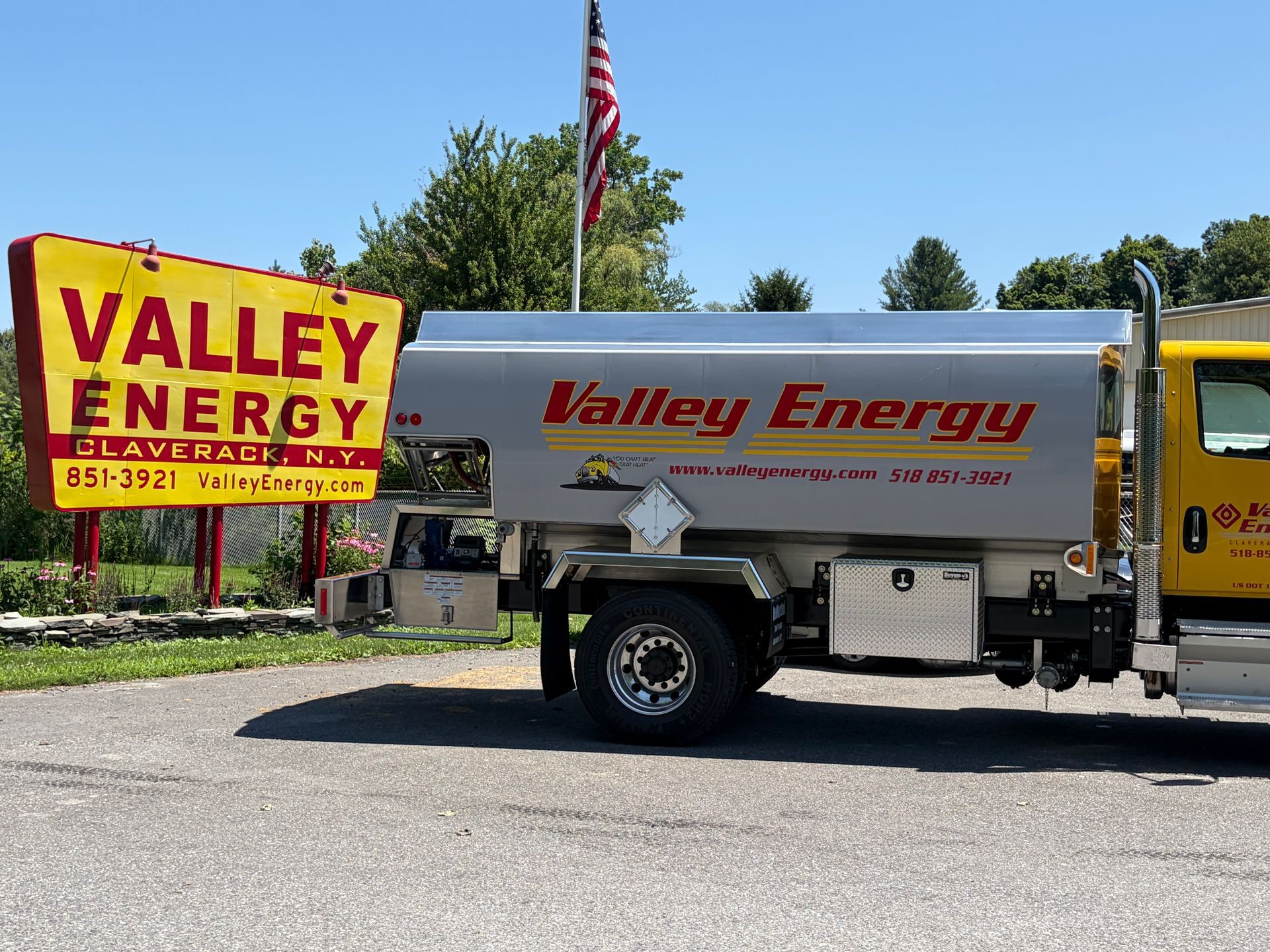 Two white Valley Energy propane tanks sit side-by-side on a stone surface outdoors beneath a wooden structure.