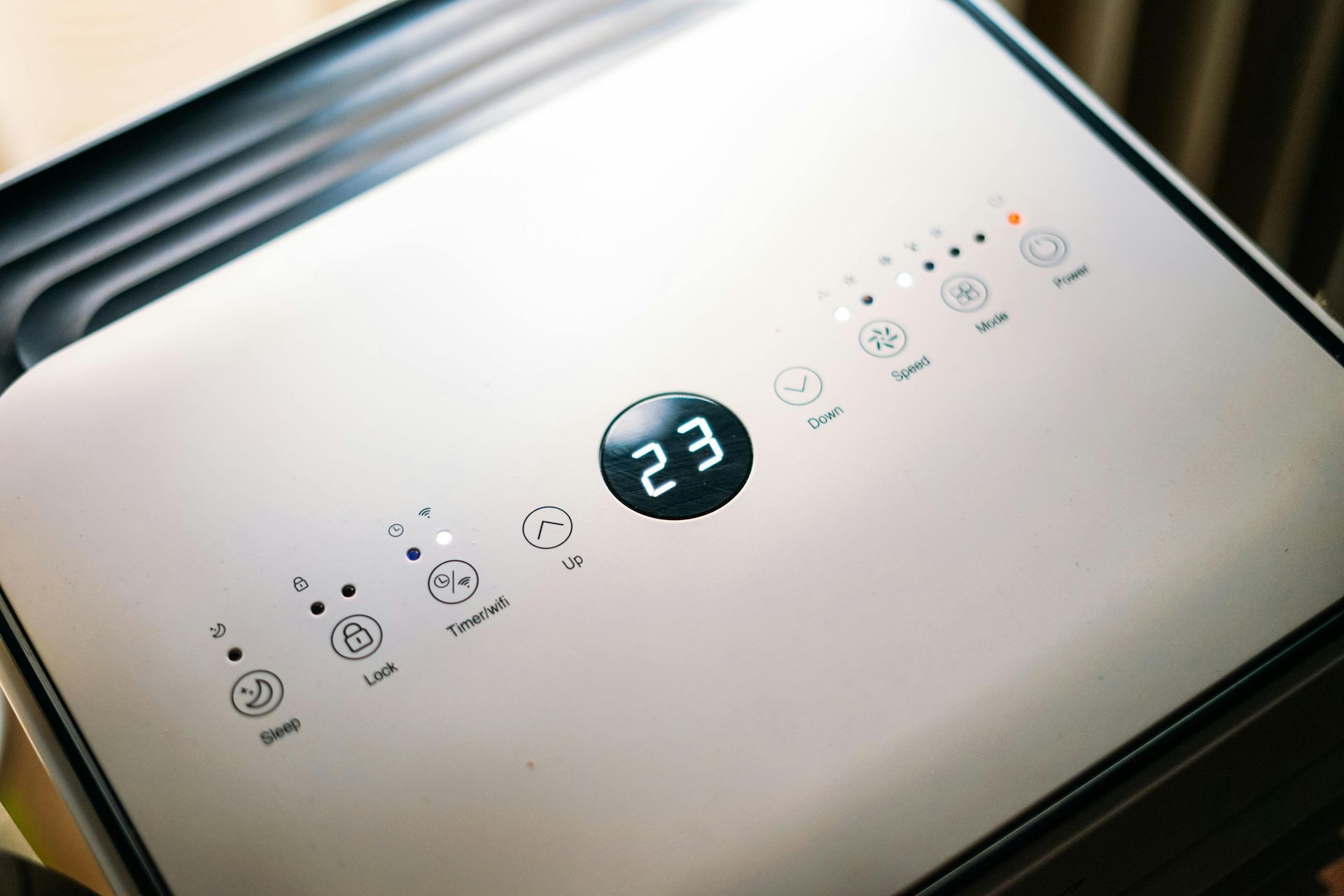 Top-down view of a white air purifier control panel with digital display showing