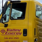 A yellow Valley Energy propane delivery truck parked outdoors with an American flag mounted on the tank.