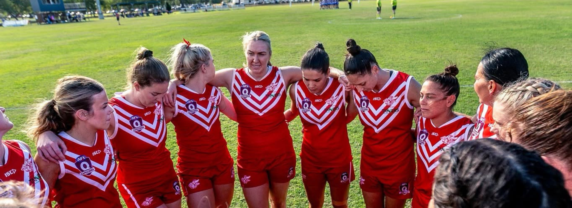 YeppoonSwans senior women standing in a circle with their arms around each other - listening to their captains speech prior to the start of the game