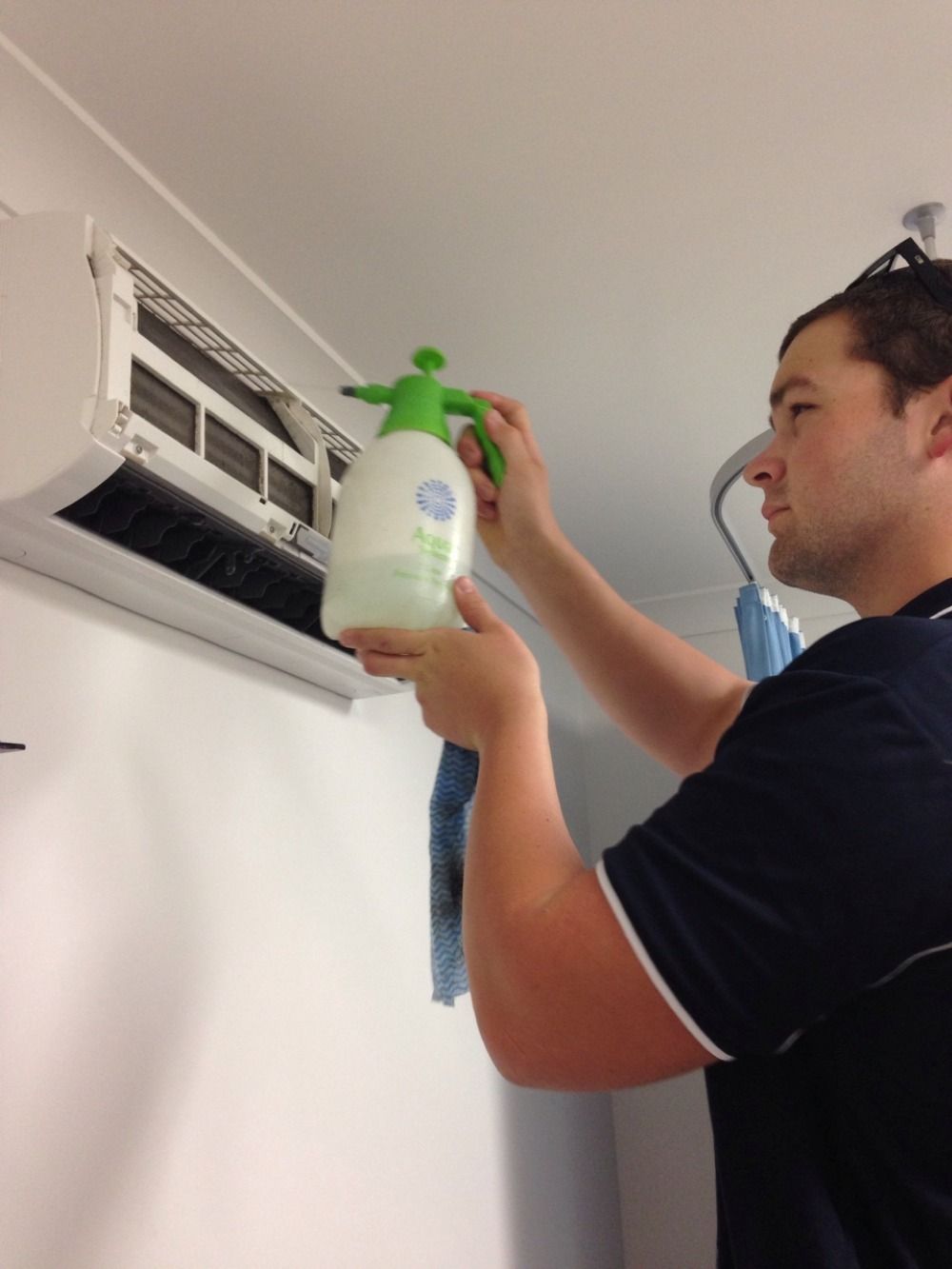 A Person Cleaning Aircon On The Wall — Allchin Airconditioning & Refrigeration Electrical in Caloundra, QLD