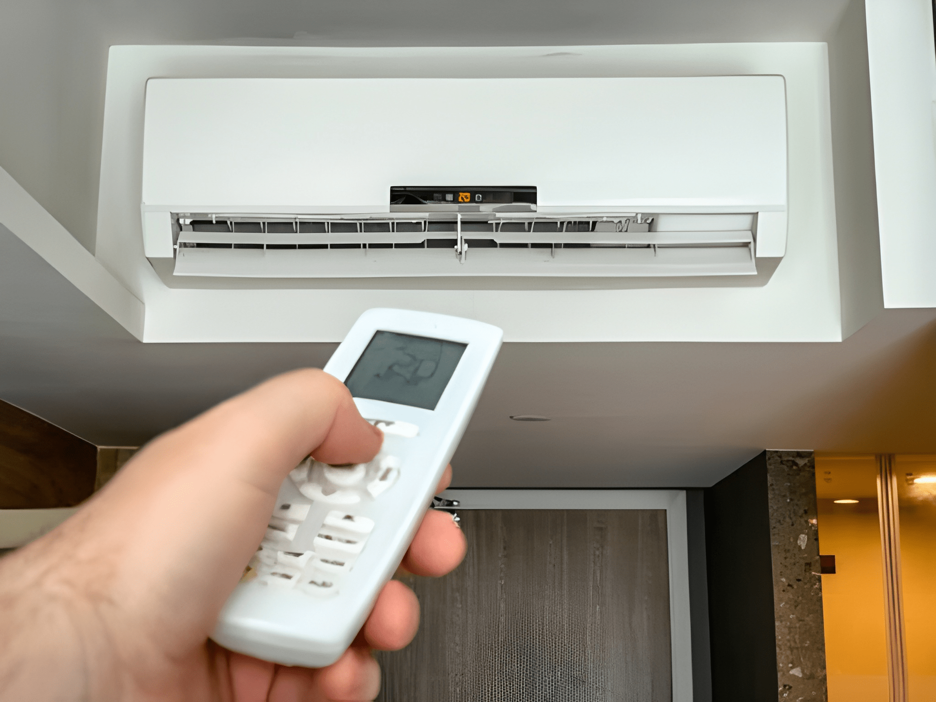 A Person Is a Remote Pointing Toward a White Wall — Allchin Airconditioning & Refrigeration Electrical in Caloundra, QLD
