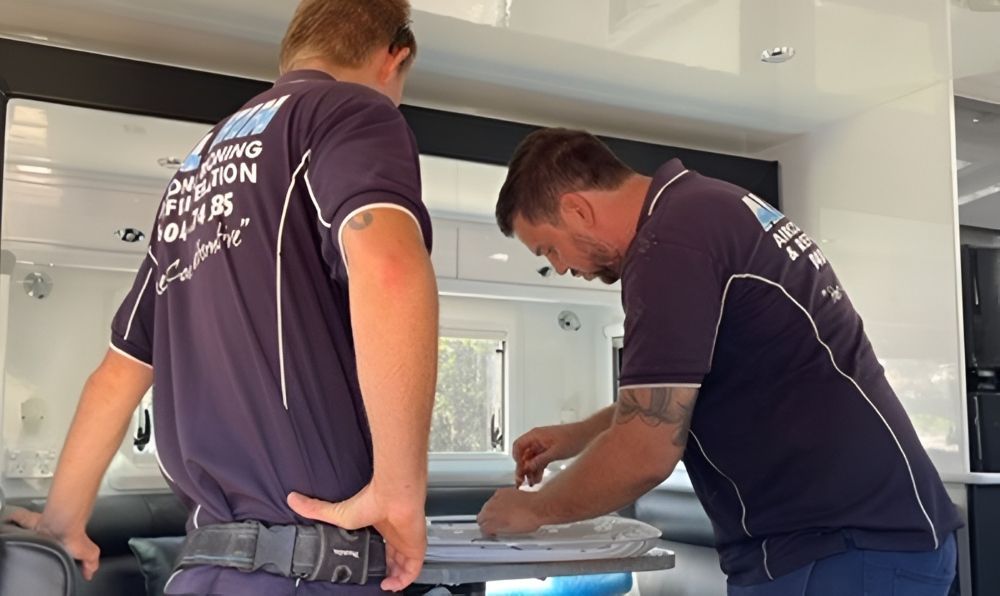 Two Men In Navy Shirts Work Inside A Caravan — Allchin Airconditioning & Refrigeration Electrical in Caloundra, QLD