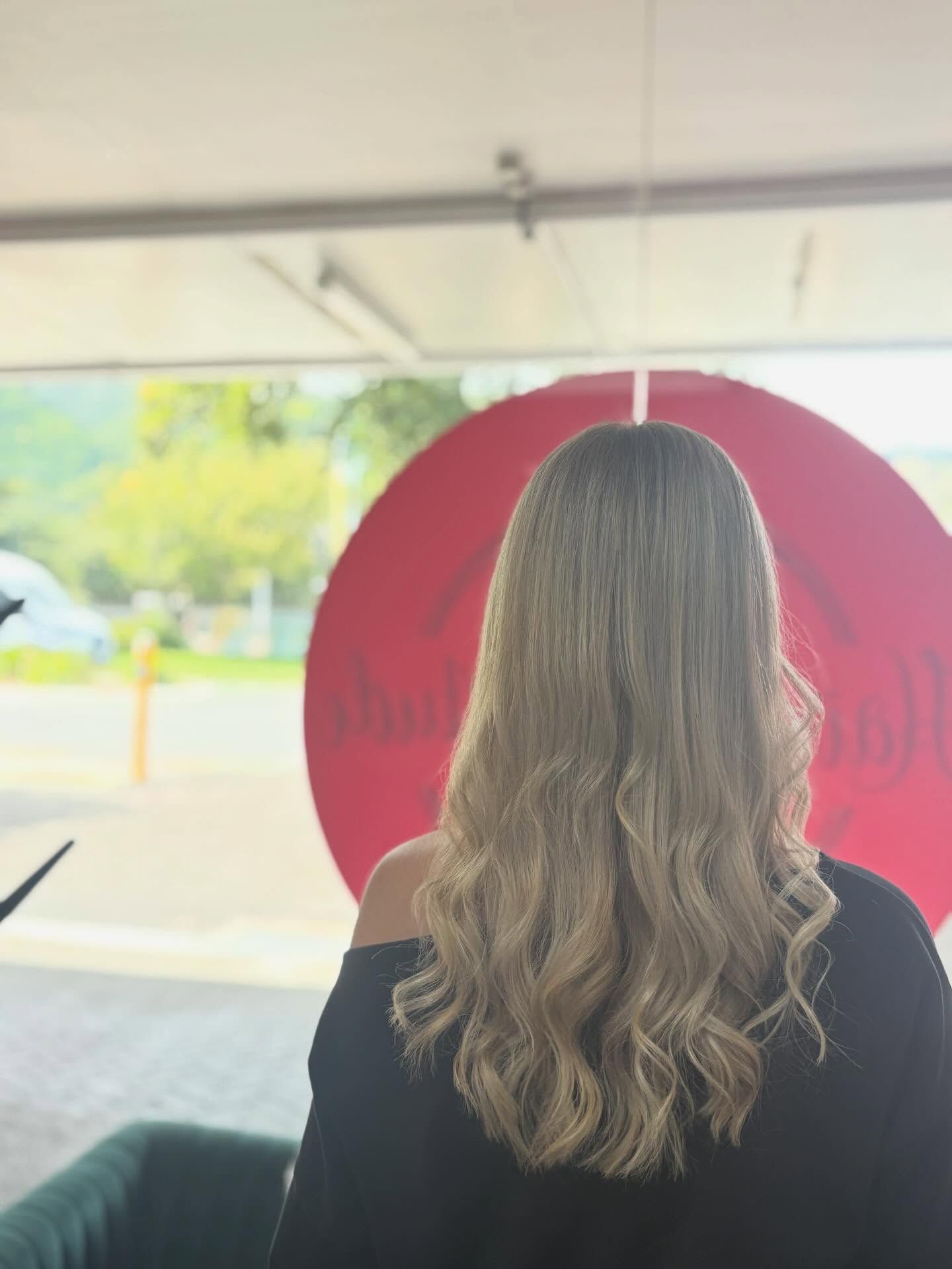 Back view of a person with wavy hair in front of a large red circular sign outdoors