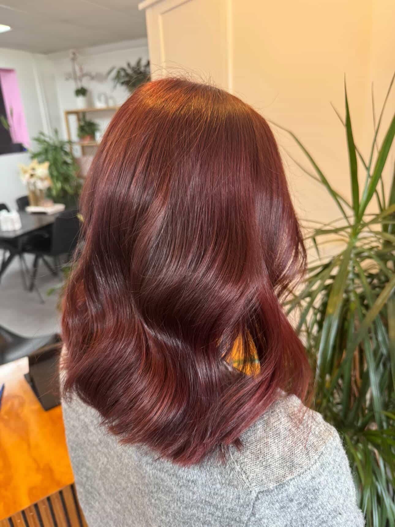 Wavy auburn bob haircut shown from behind in a bright indoor setting