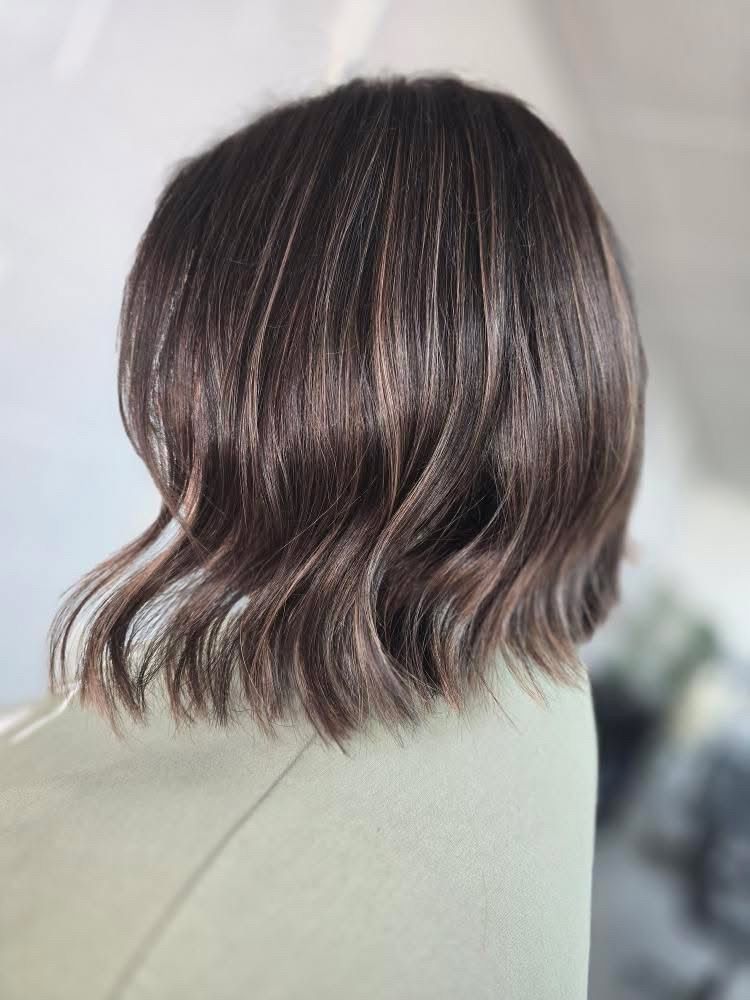 Short wavy dark brown bob haircut viewed from the back against a light background