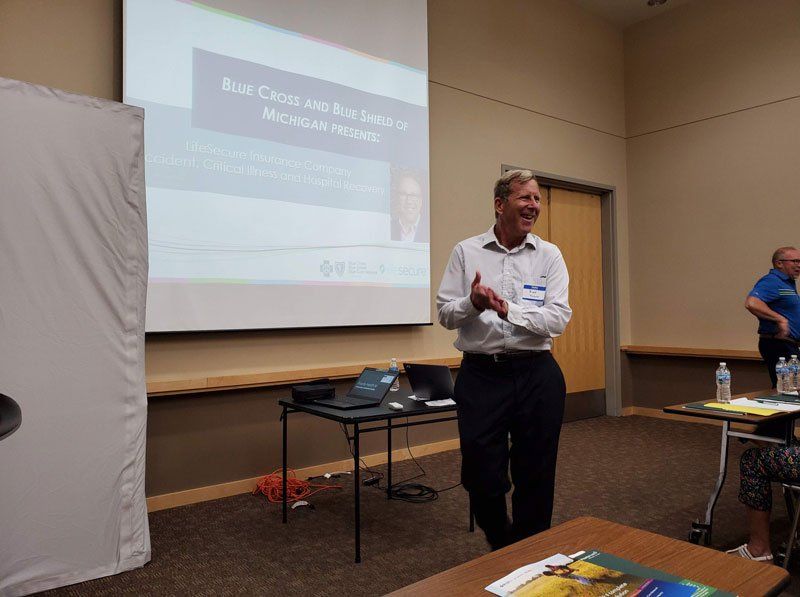 A man is giving a presentation in front of a projector screen