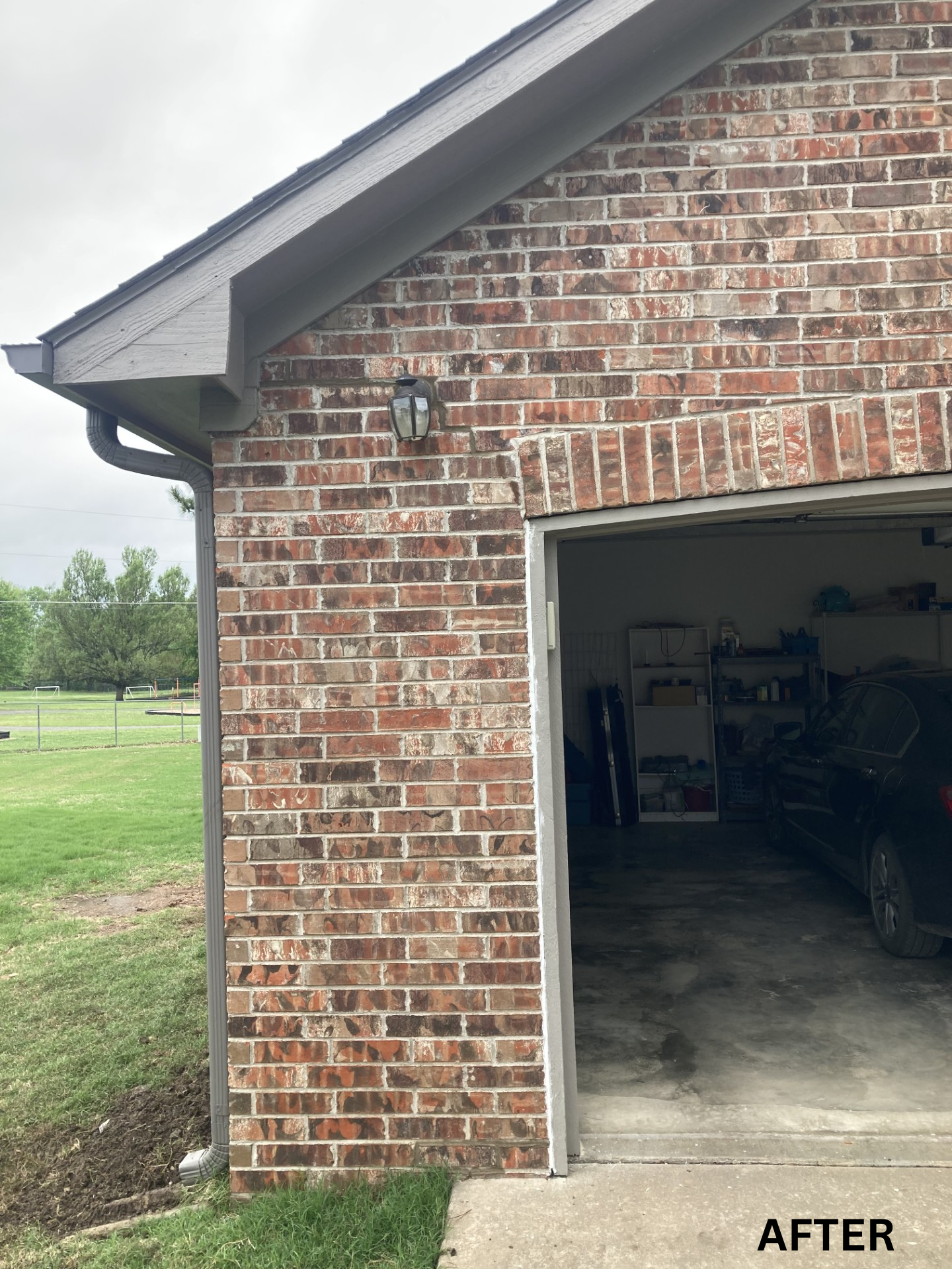 Brick garage exterior with open door, showing the interior and green yard beside it.