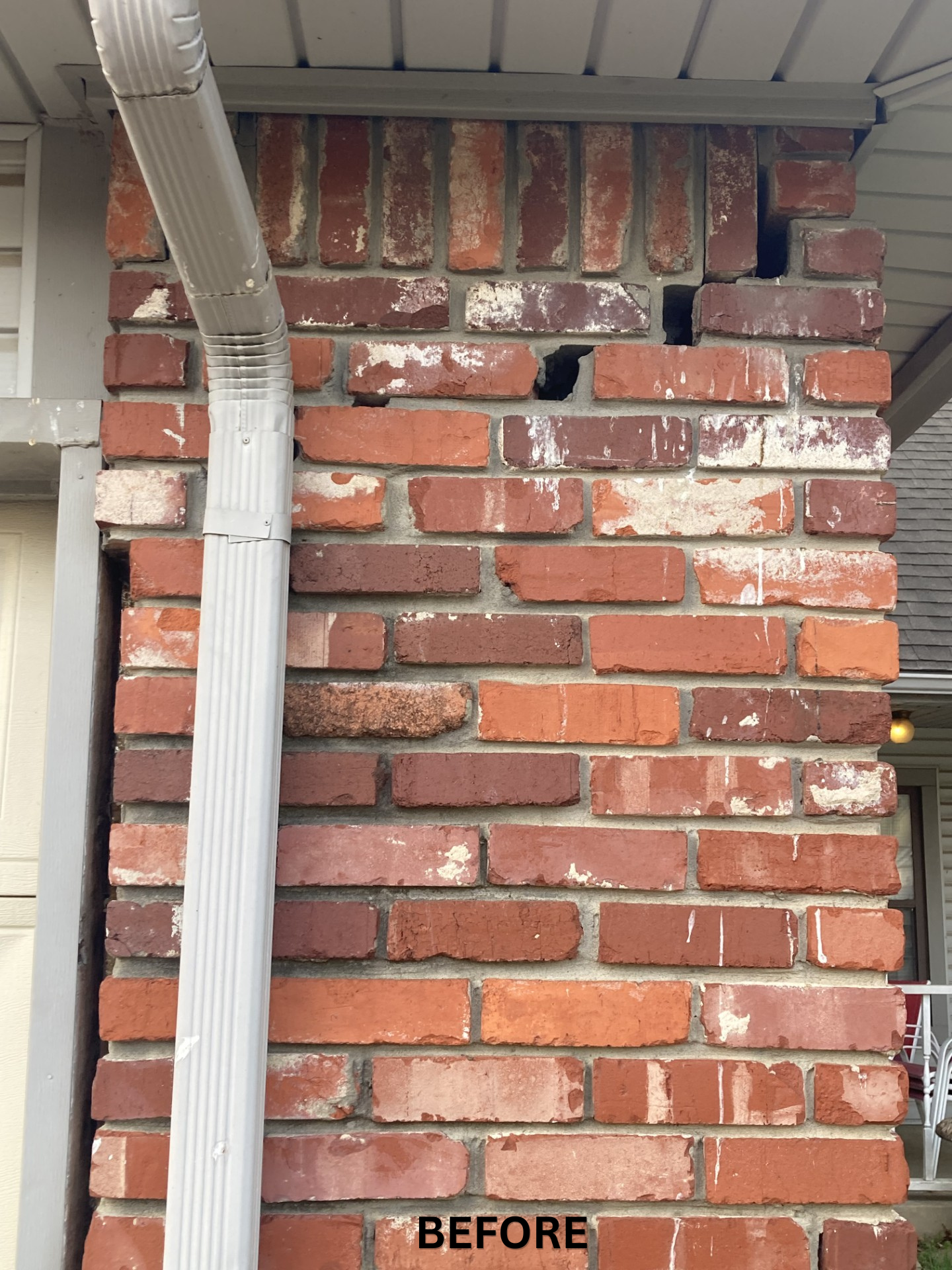 Red brick wall corner with a white gutter and downspout, labeled “BEFORE” at the bottom.