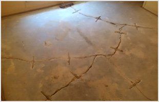 A concrete floor with a large crack repaired by steel staples across the fracture line.