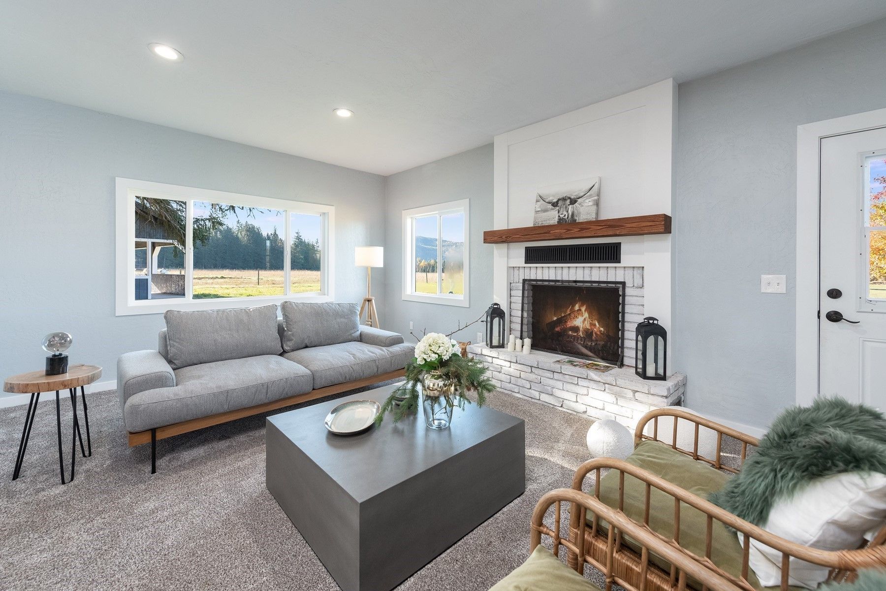 Bright living room with gray sofa, fireplace, coffee table, and large window