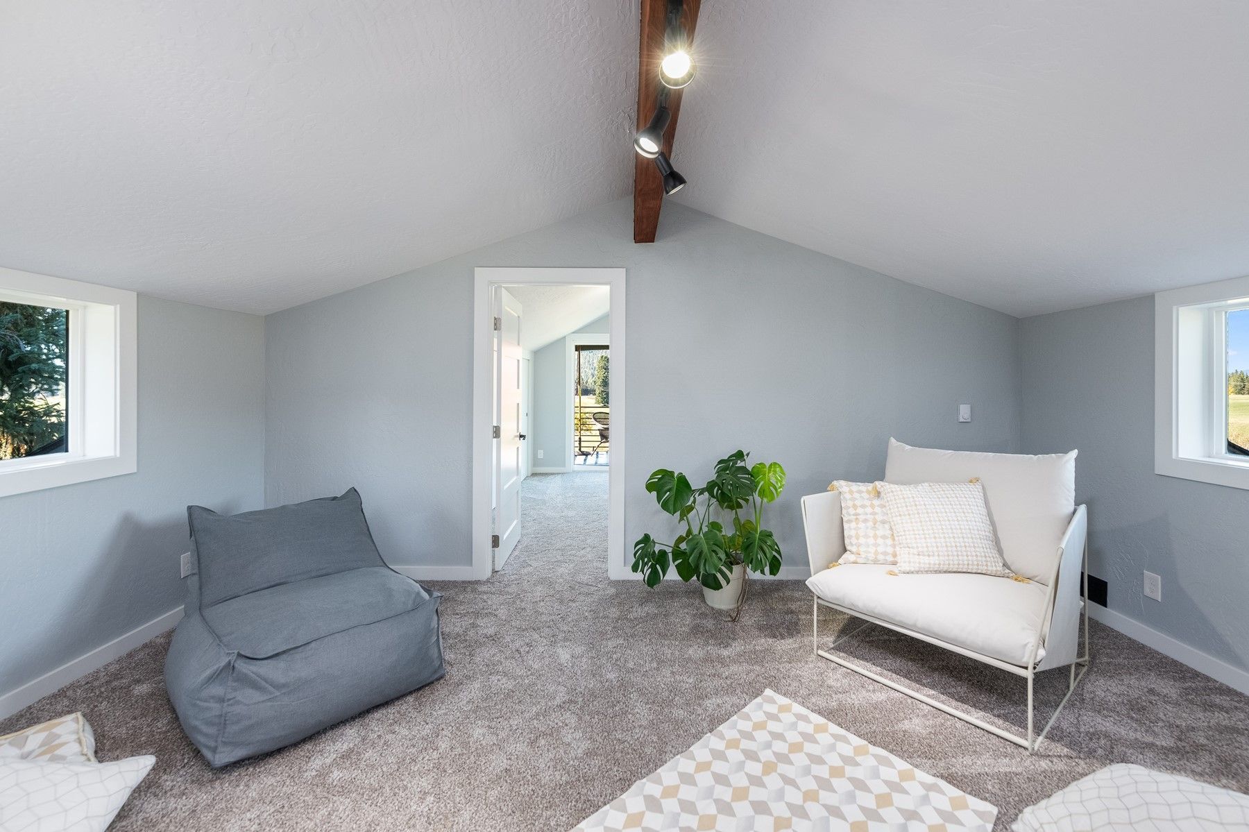 Bright gray loft room with carpet, small windows, and two lounge chairs