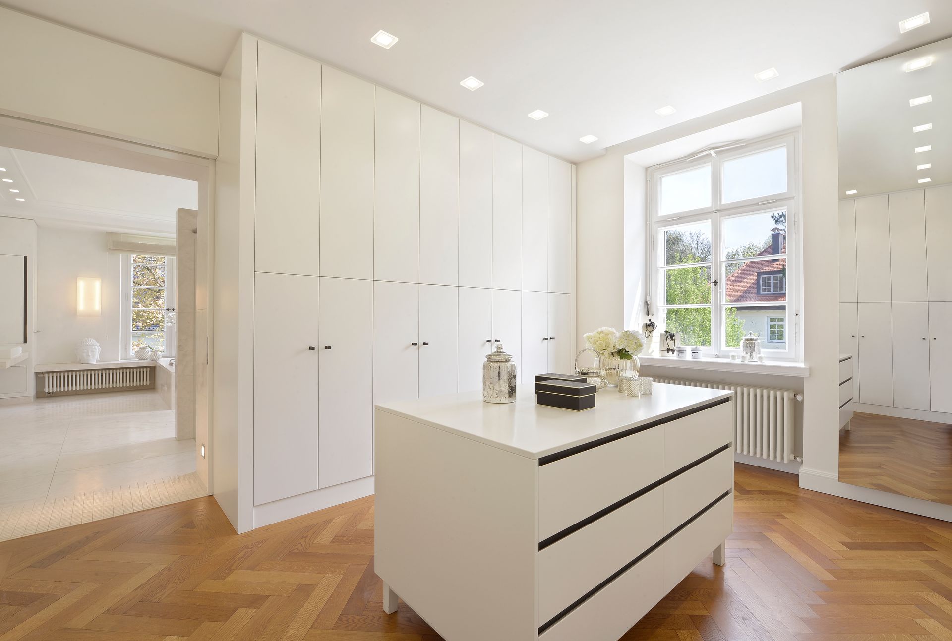 Bright modern kitchen with white cabinets, a central island, and large window overlooking houses