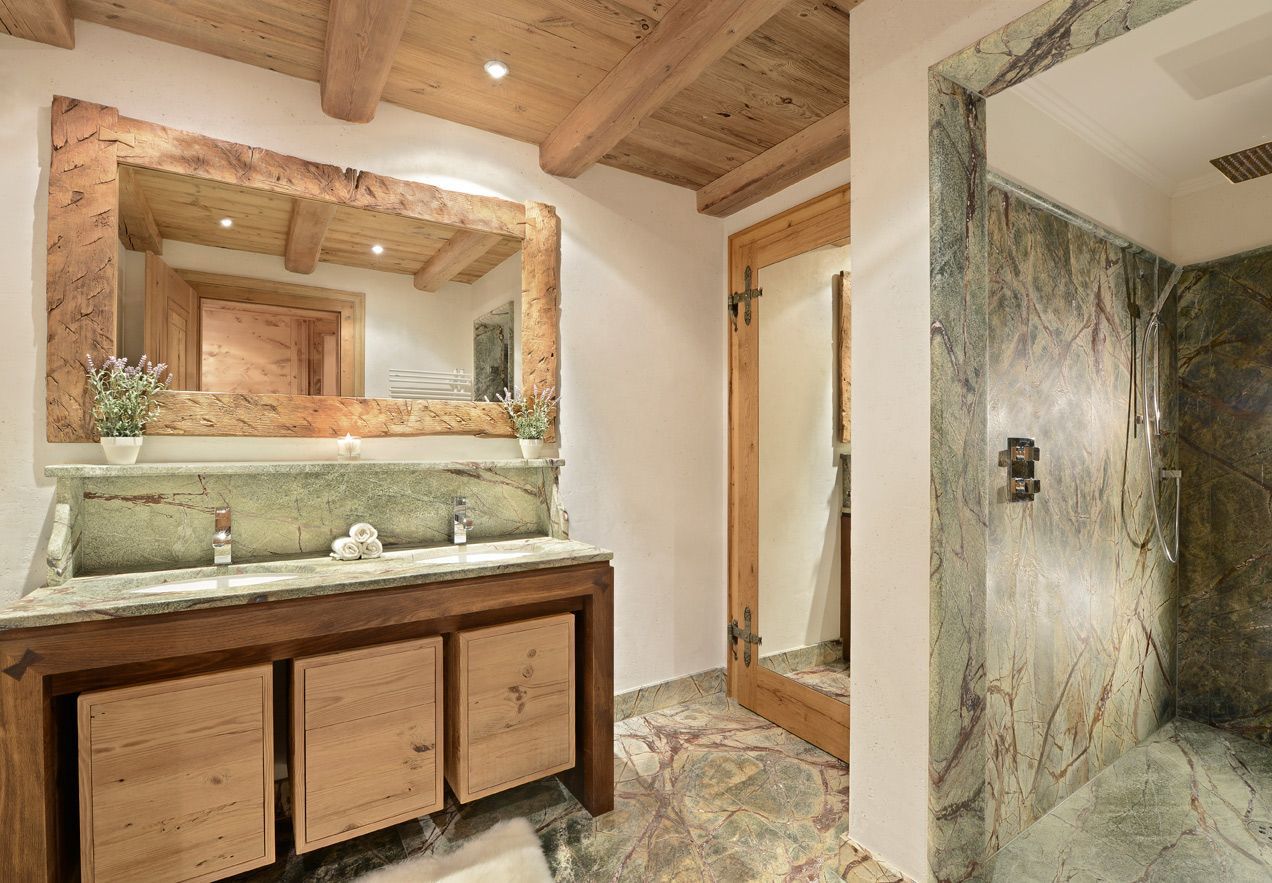 Rustic bathroom with wood-beam ceiling, double vanity, large mirror, and tiled walk-in shower