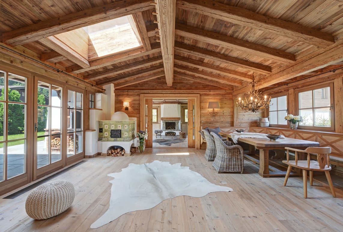 Rustic wooden cabin living room with skylight, large windows, and a white rug on the floor