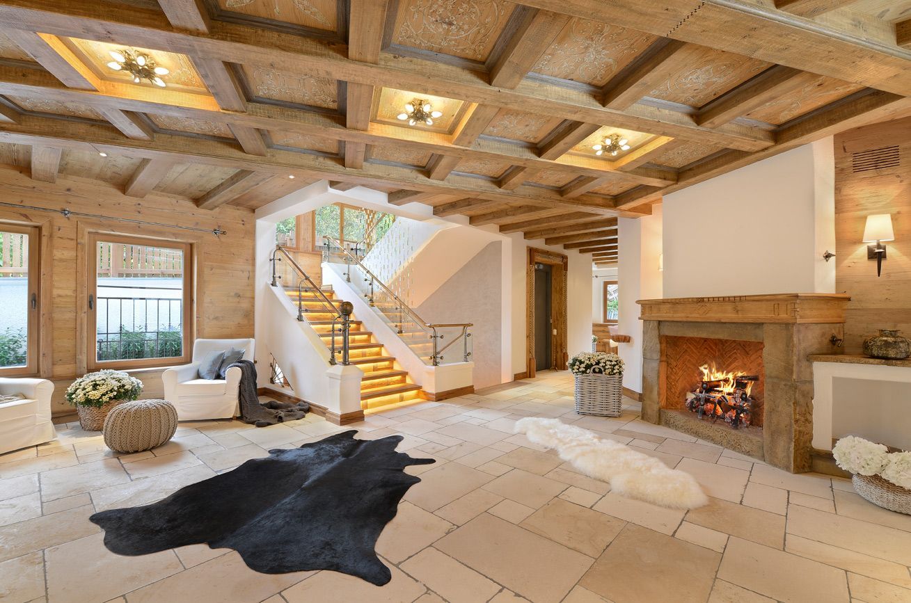Bright living room with exposed wood beams, staircase, fireplace, and black cowhide rug