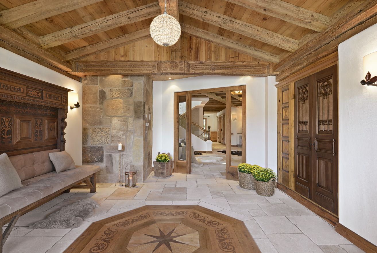 Stone entryway with carved wood ceiling, bench seating, and an open doorway to a bright interior courtyard.