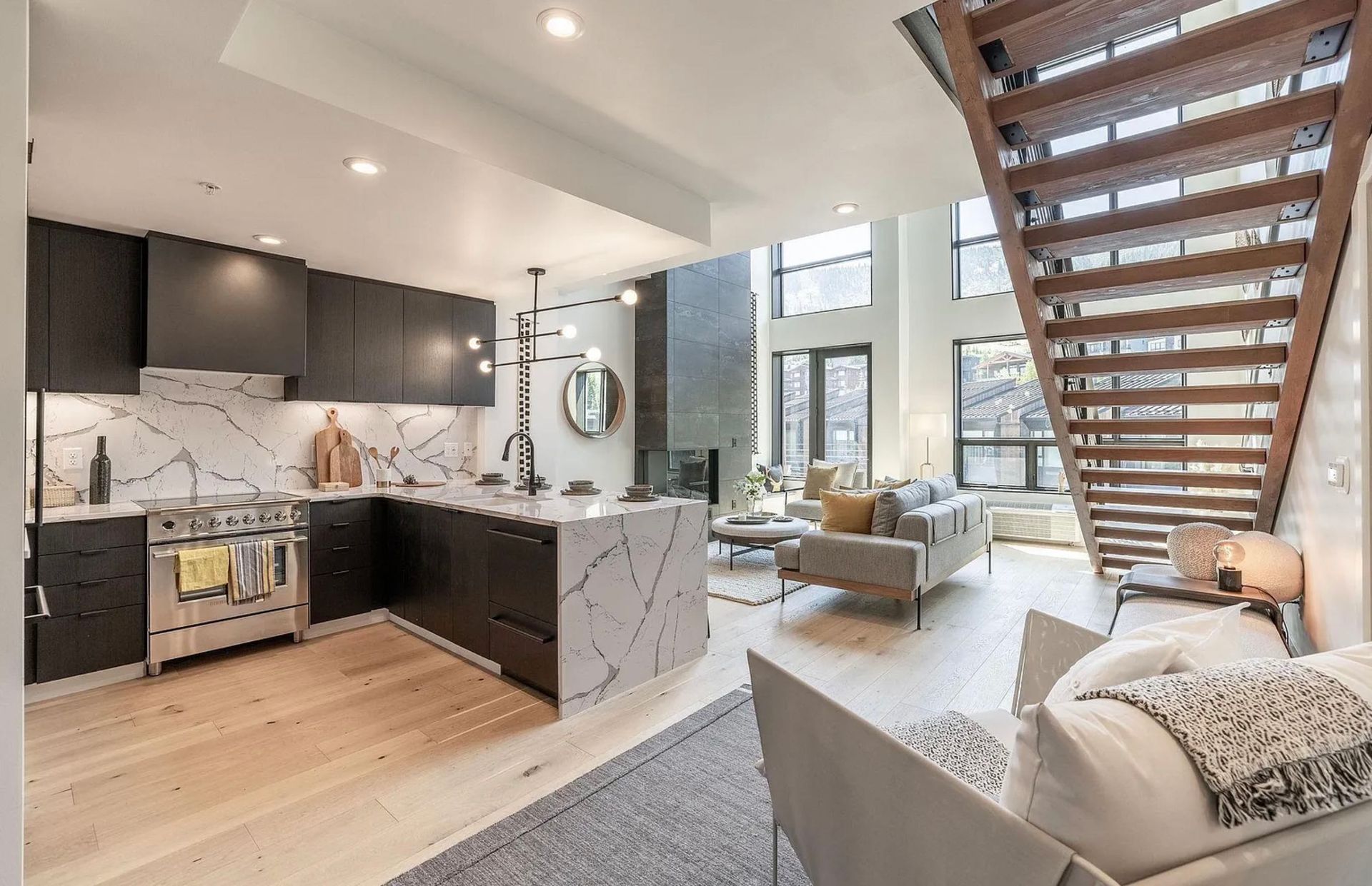 Modern loft interior with open kitchen, staircase, and sunlit living area