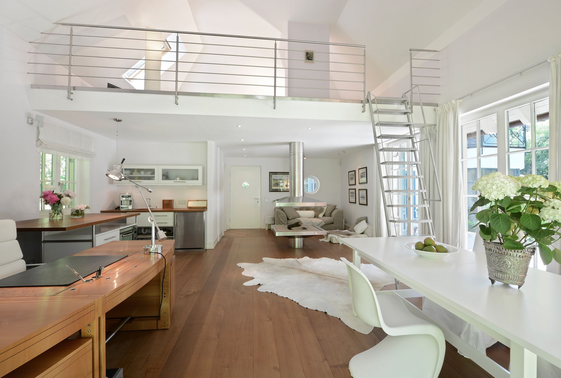 Bright modern kitchen with wood floors, white dining table, island, and large windows