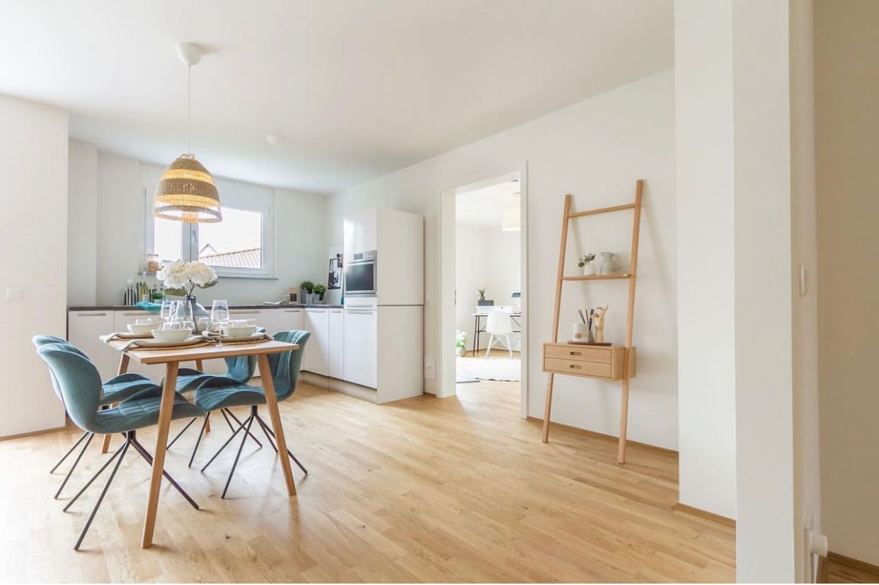 Bright dining and kitchen area with wooden table, blue chairs, and light wood floors