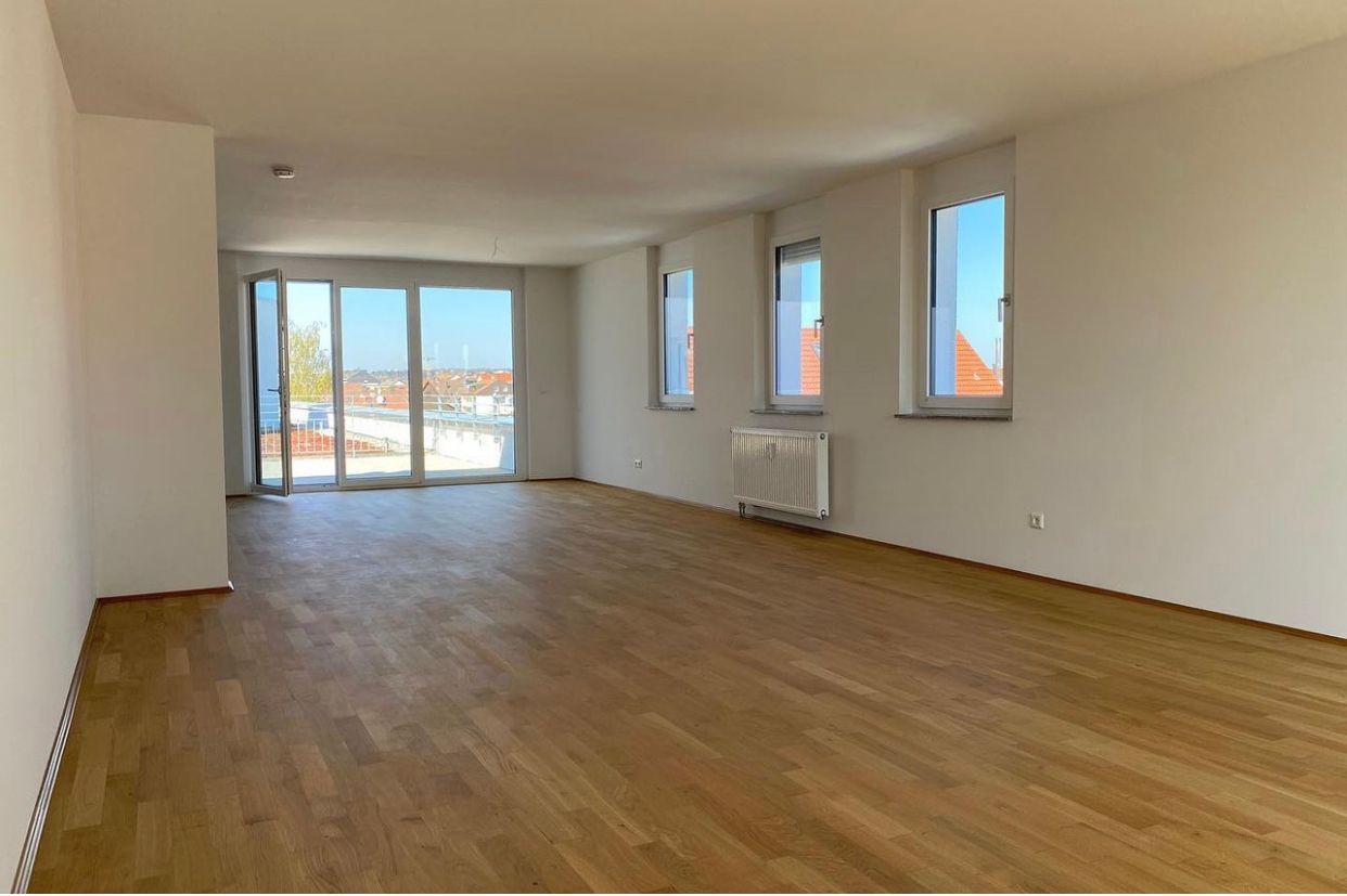 Empty modern apartment living room with wood floors, white walls, and large windows with city view