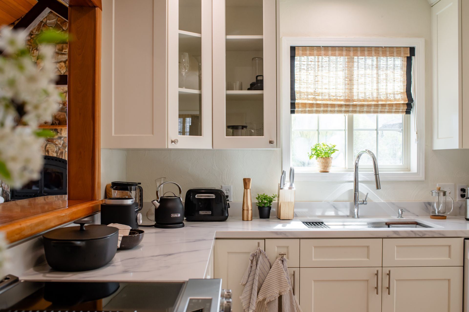 Bright kitchen with white cabinets, stove, sink, and window with a woven shade