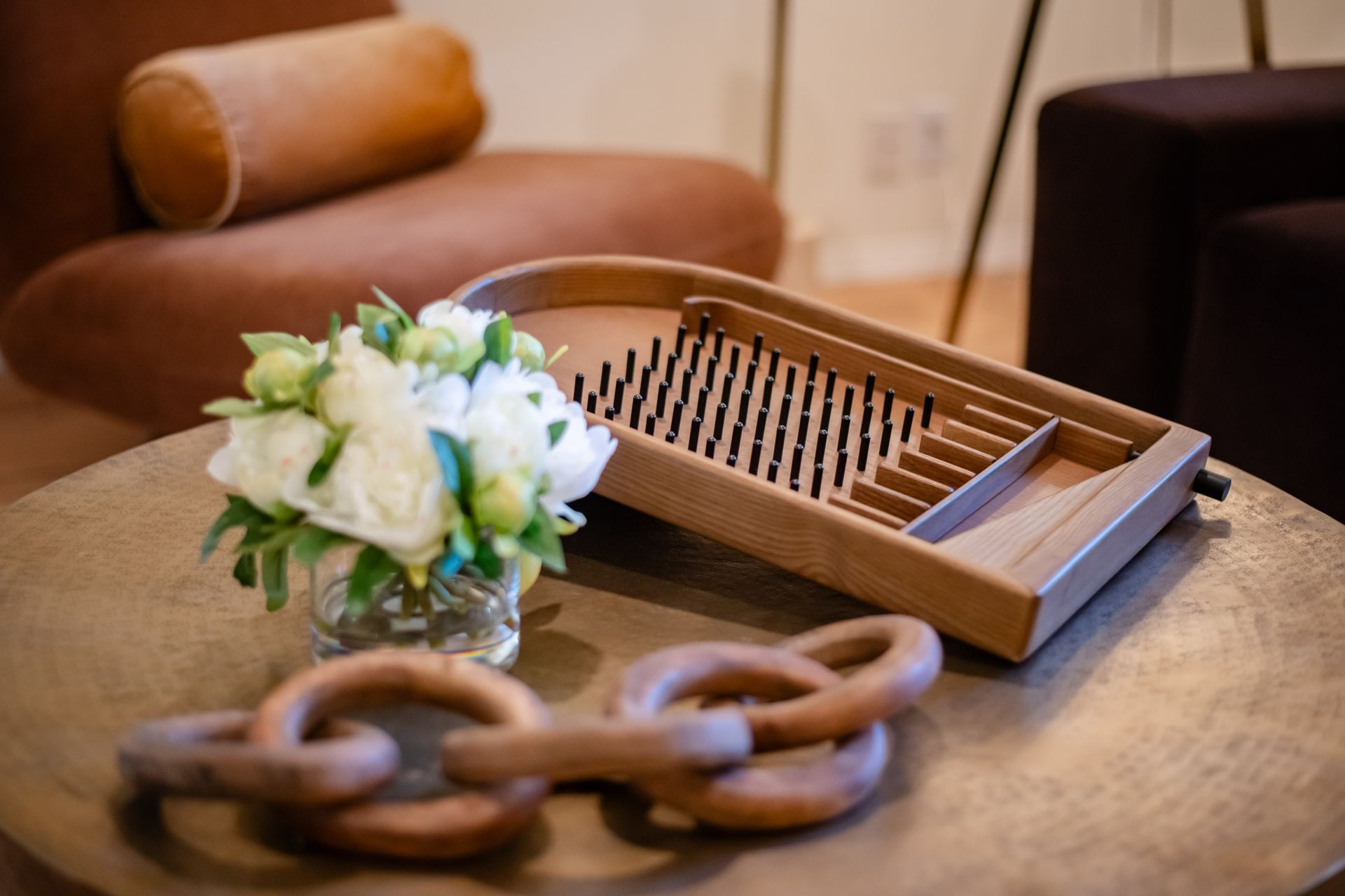 Wooden tray, flowers, and chain-link decor on a coffee table in a cozy living room
