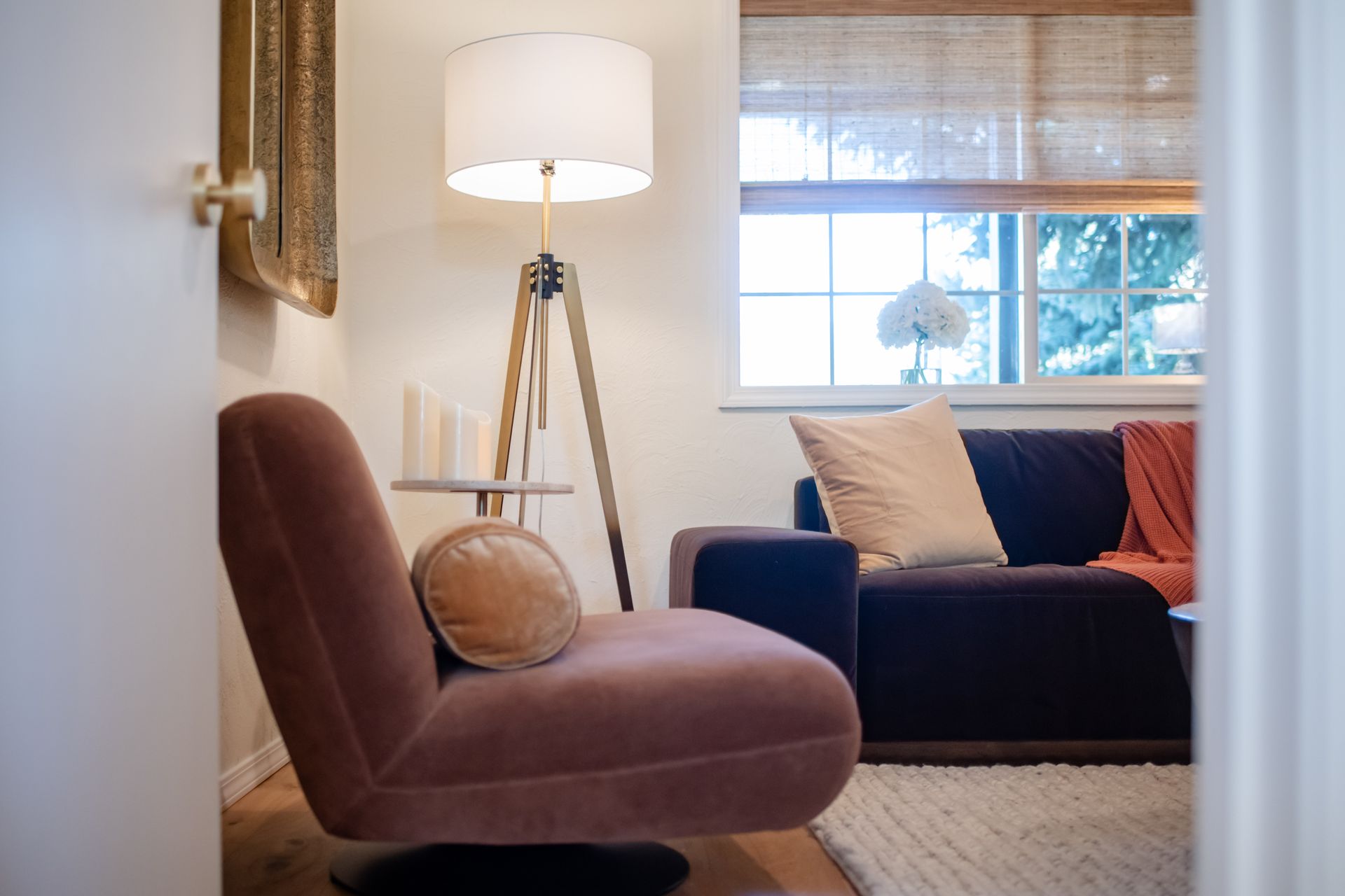 Cozy living room with a mauve chair, floor lamp, window, and dark sofa with pillows