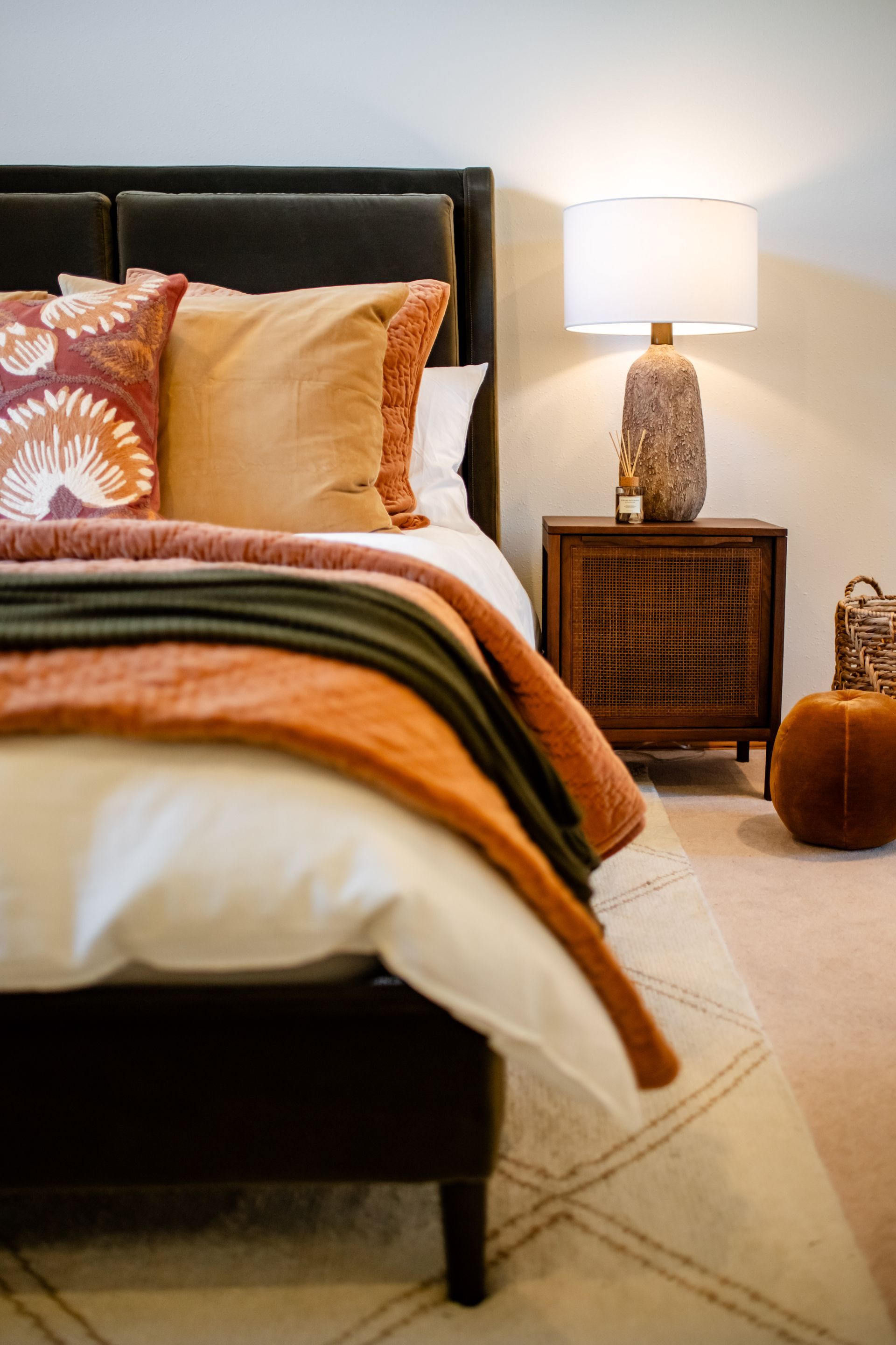 Cozy bedroom corner with surrey olive bed, hazel bedding, bedside lamp, and woven nightstand