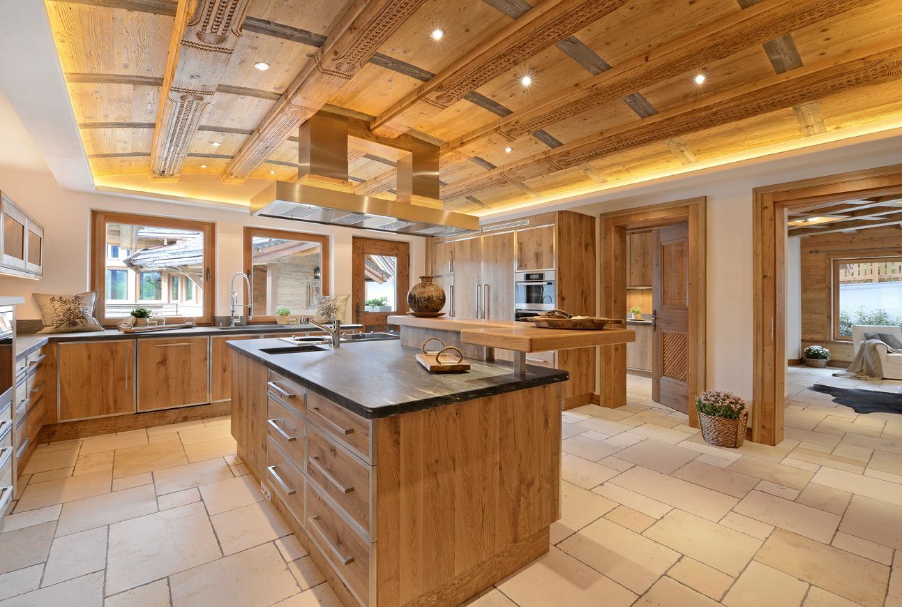 Spacious modern kitchen with wood cabinetry, tiled floor, and a large central island under warm lighting
