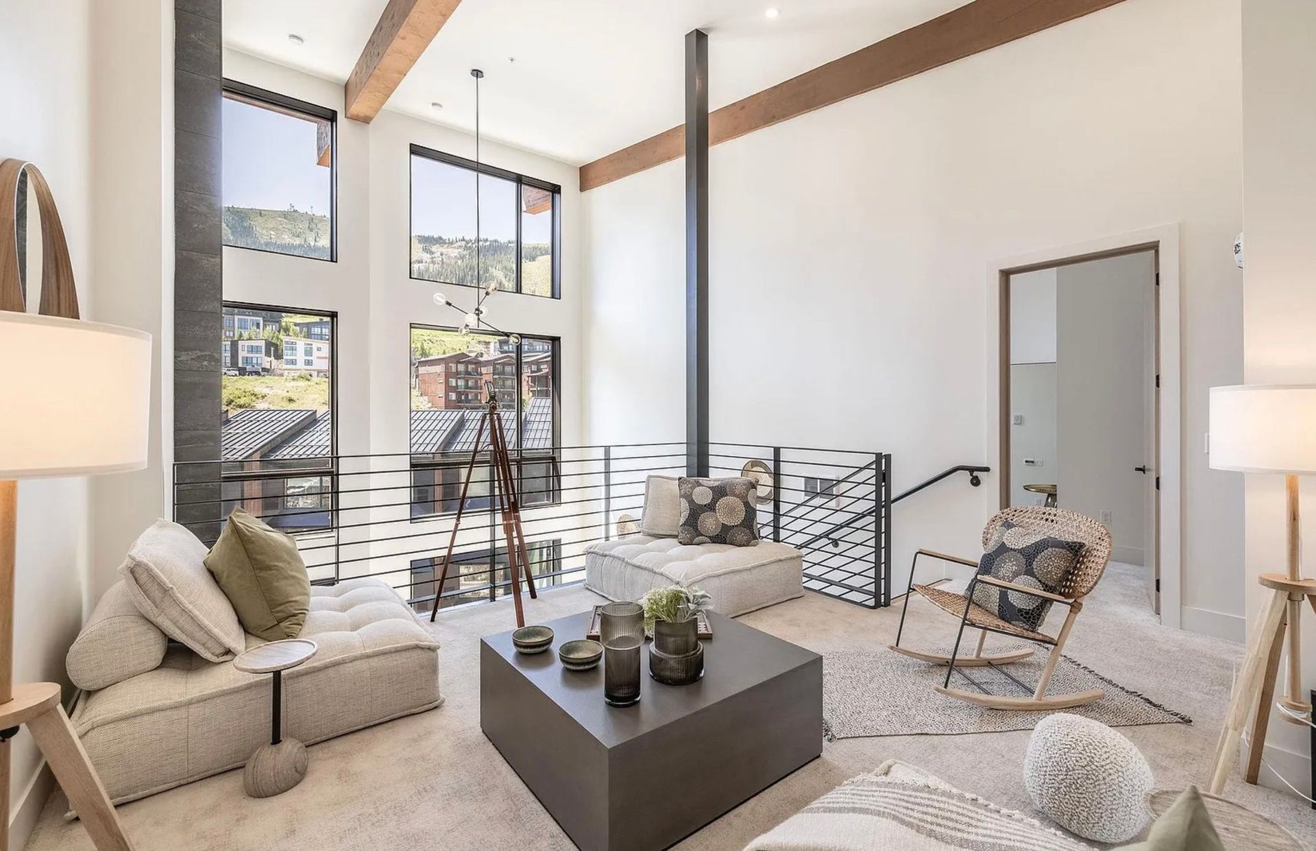Top-down view of a cozy living room with a gray sofa, white chairs, rug, coffee table, and cushions.
