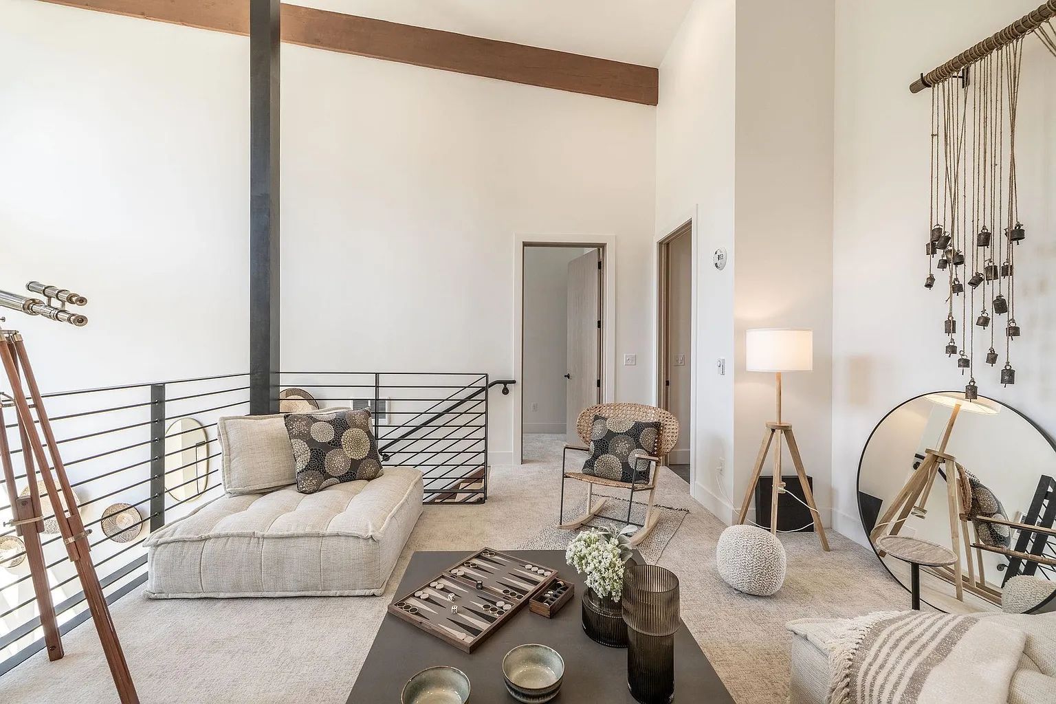 Bright modern living room with white sofas, patterned pillows, and a loft railing by large windows