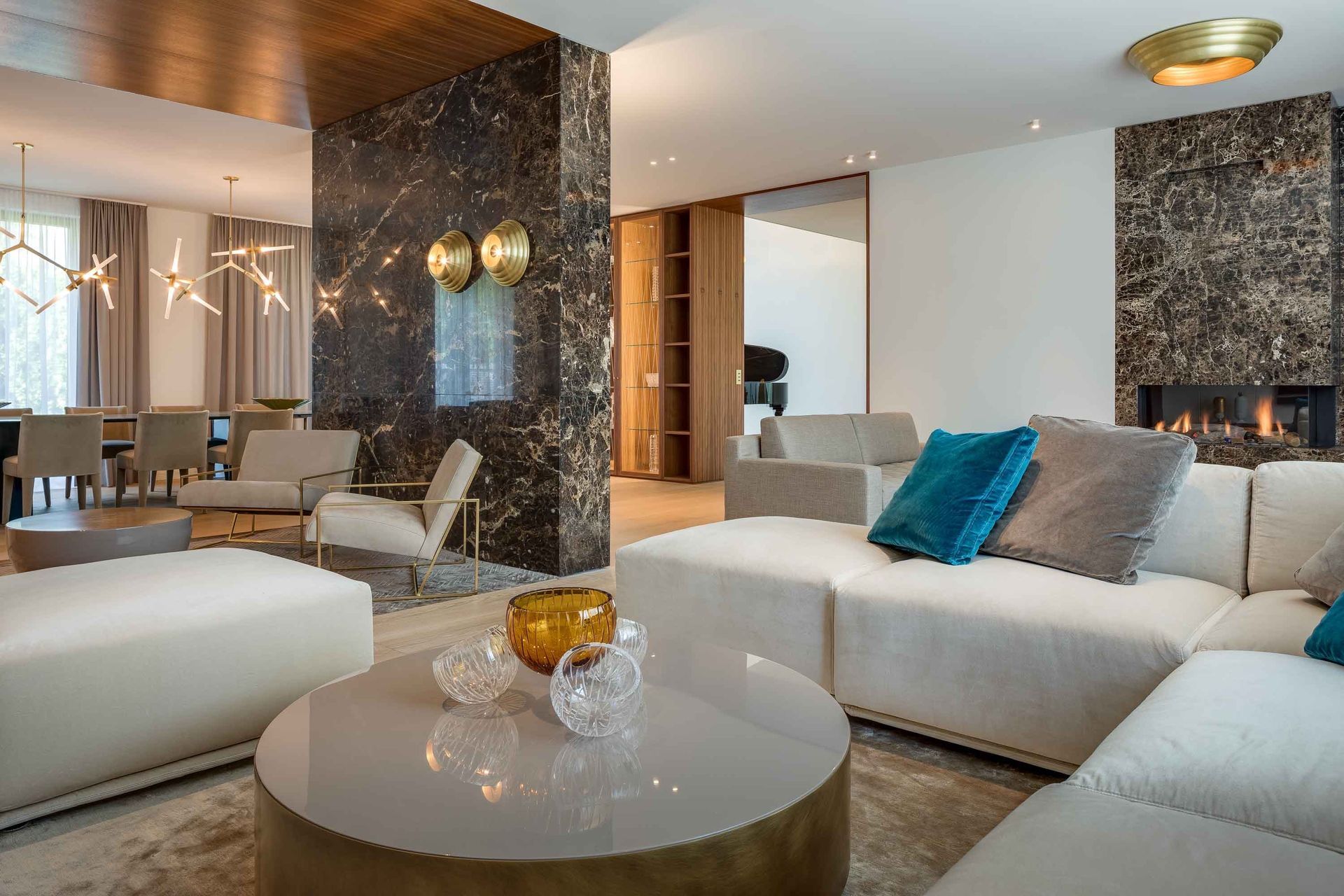Modern luxury living room with white sofas, round coffee table, and dark marble accent walls