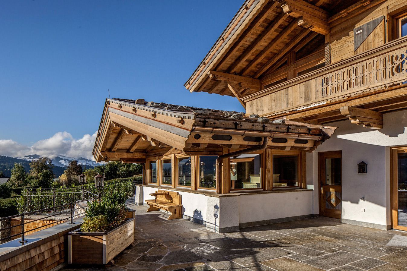 Wooden chalet with carved balconies on a sunny mountain terrace under a blue sky