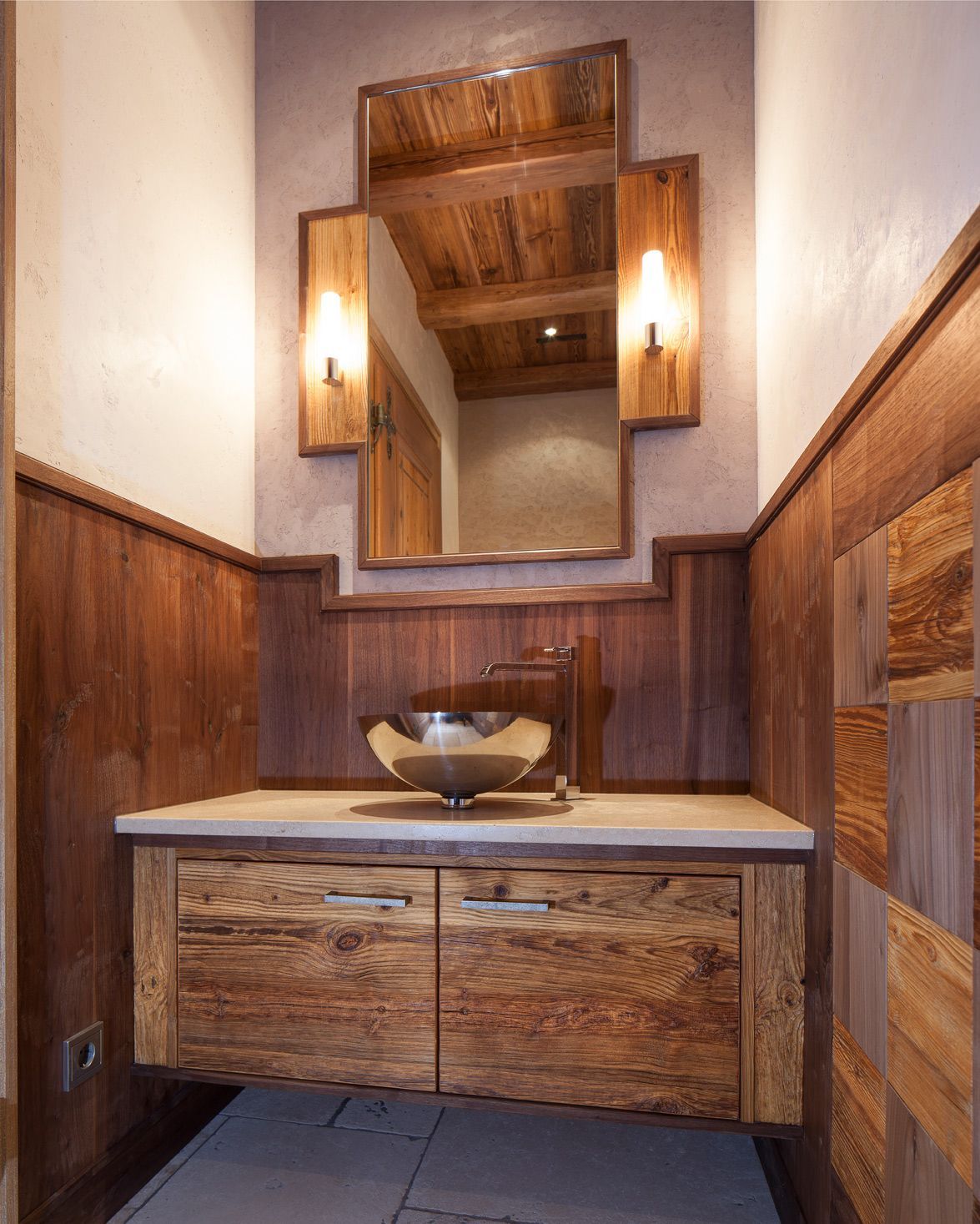 Rustic bathroom vanity with wood paneling, mirror, vessel sink, and wall sconces
