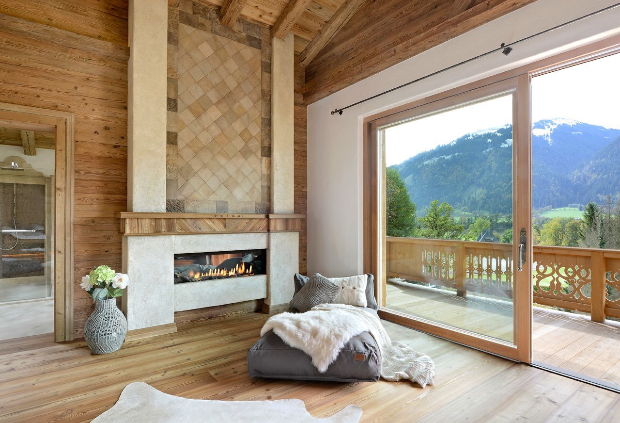 Cozy wood-paneled living room with fireplace, floor cushion, and large window overlooking mountains