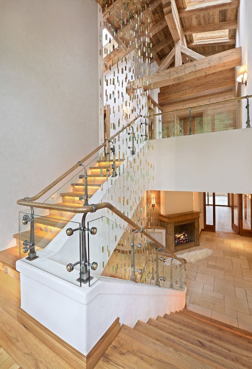 Modern home staircase with glass railing, wood steps, and warm interior lighting