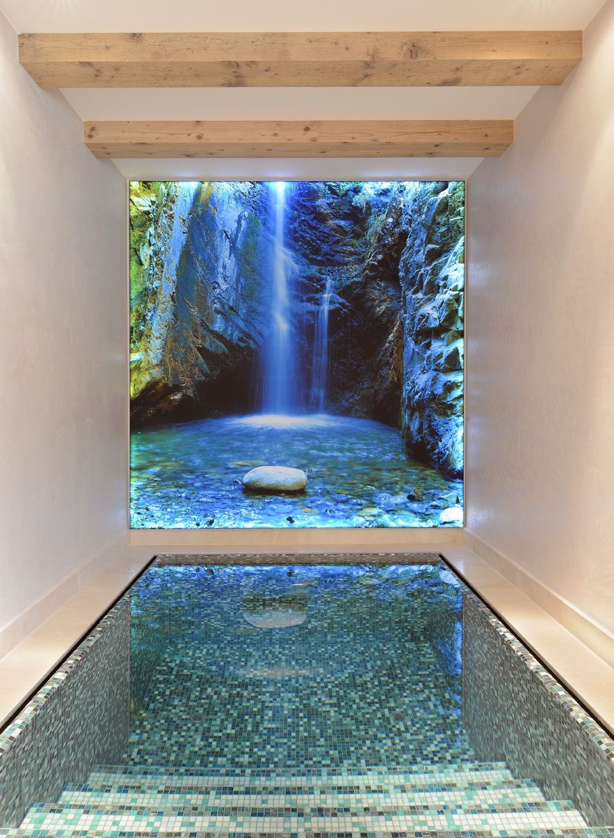 Indoor spa room with glass floor and a waterfall view beyond the opening